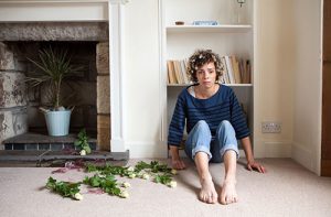 Image of woman looking fearful with vase shattered beside her
