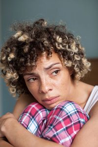 Image of woman in pyjamas hugging her knees