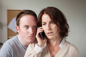 Photograph of man listening on on woman's phone conversation.
