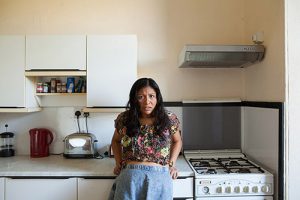 photograph of scared woman backed against kitchen counter.
