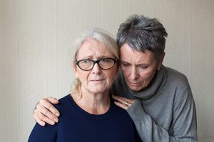 photograph of older woman comforting another.
