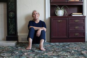 image of older woman sitting on floor looking sad